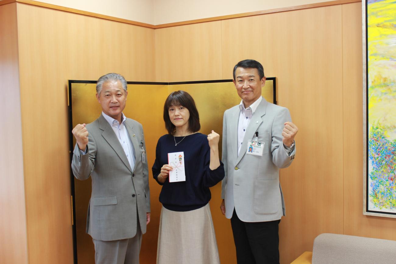 男性2名の中央に酒井由美さんが立ち、3名でガッツポーズをしている写真