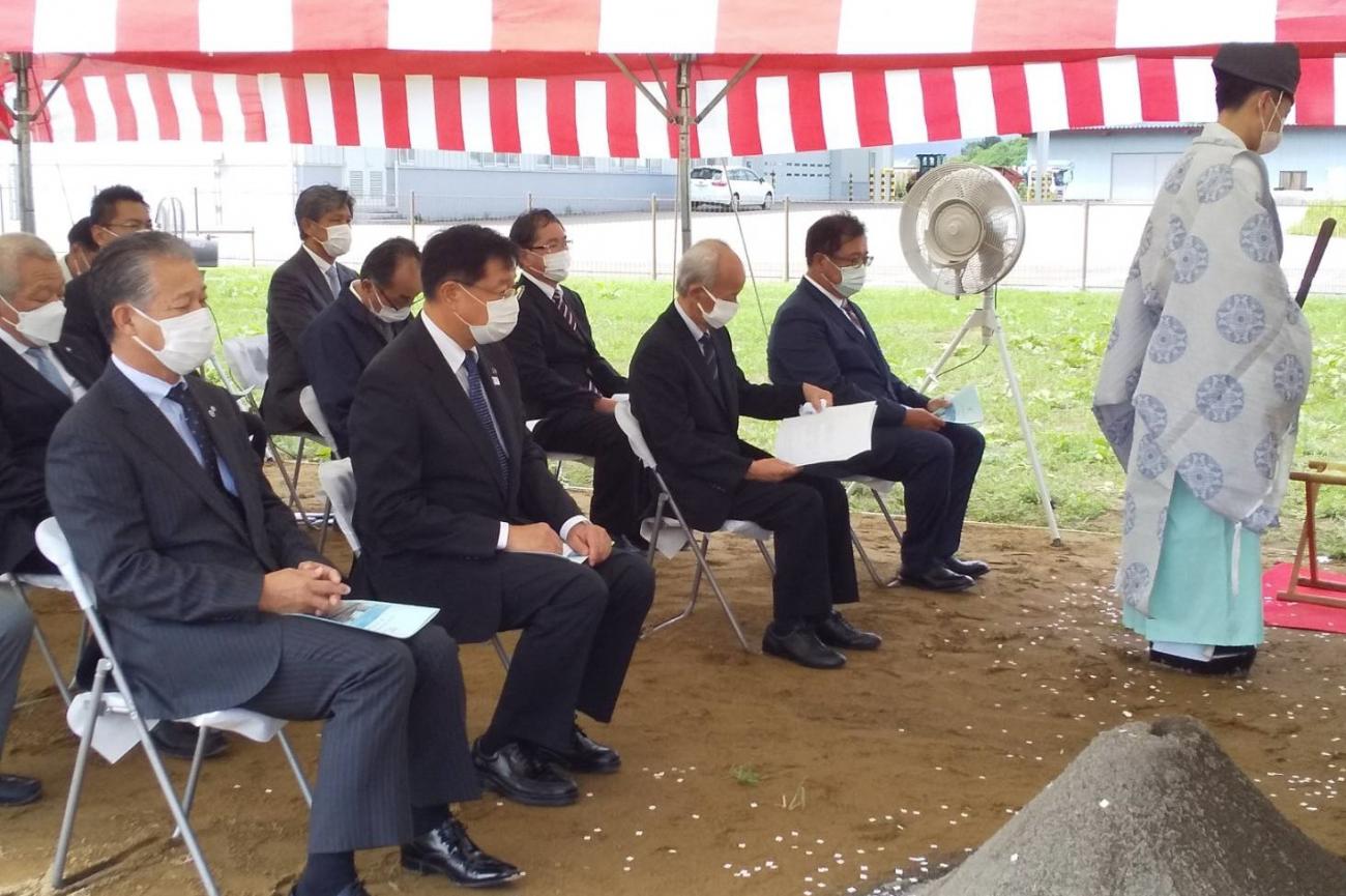 前方に袴を着て立っている神主と、手元に資料を持ちパイプ椅子に座っている関係者の方々の写真