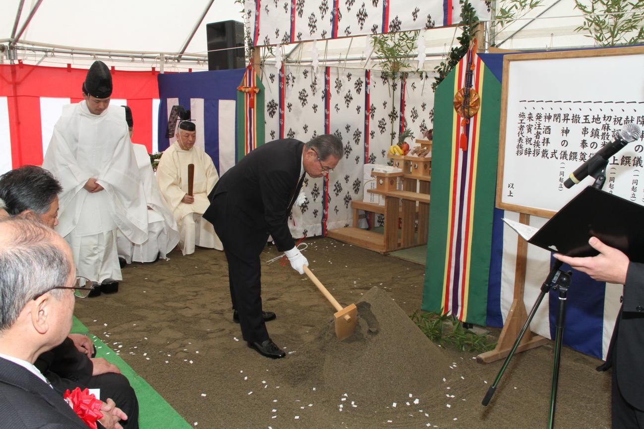 地鎮祭で神主さんの前で町長が鍬入を行っている写真