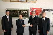 議長室でスーツ姿の男性4人が横一列に並び、中央の町長と議長が回答書を一緒に持っている写真