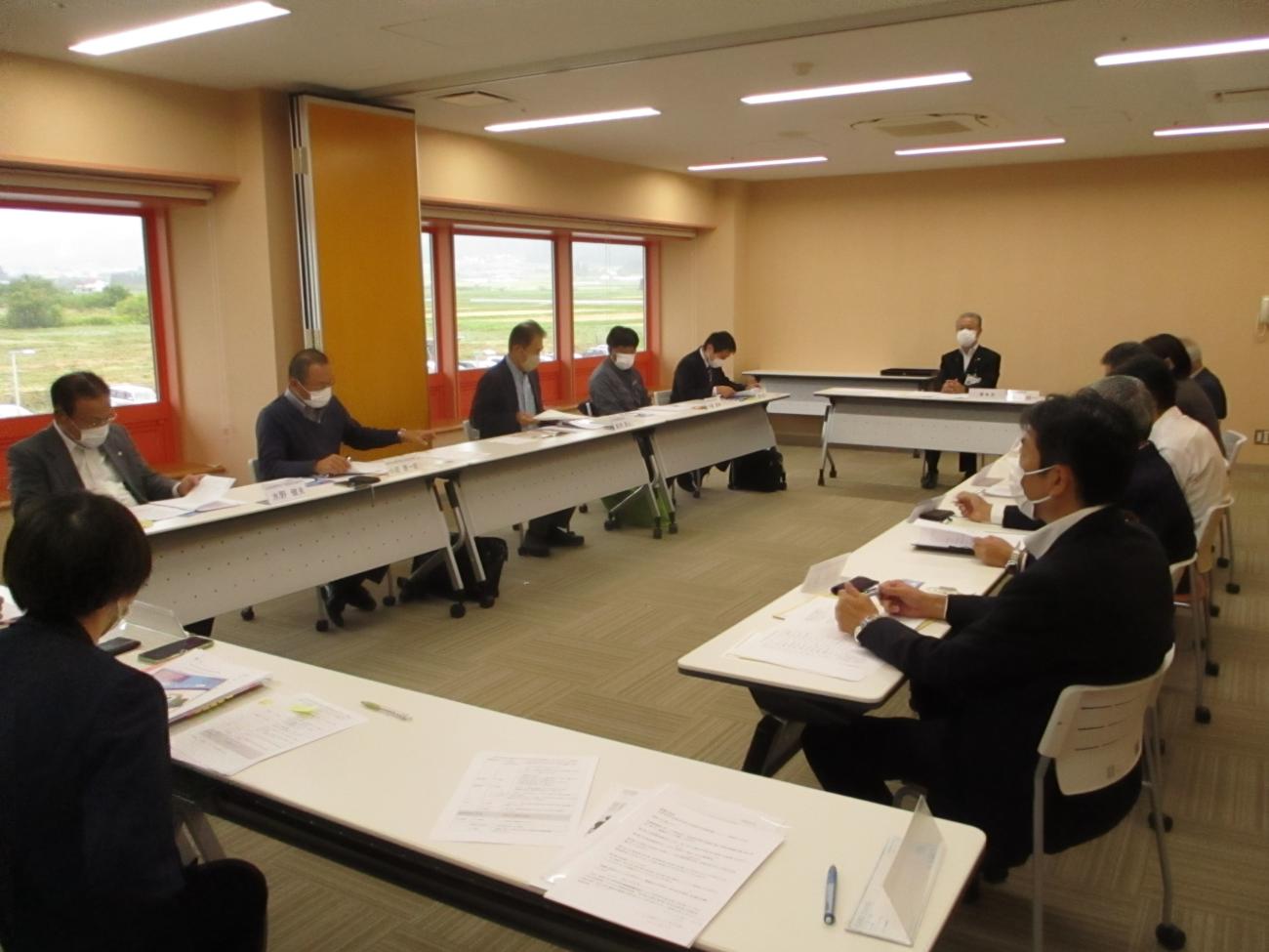 関係者がロの字型に設置された長机に着席し、会議をしている写真