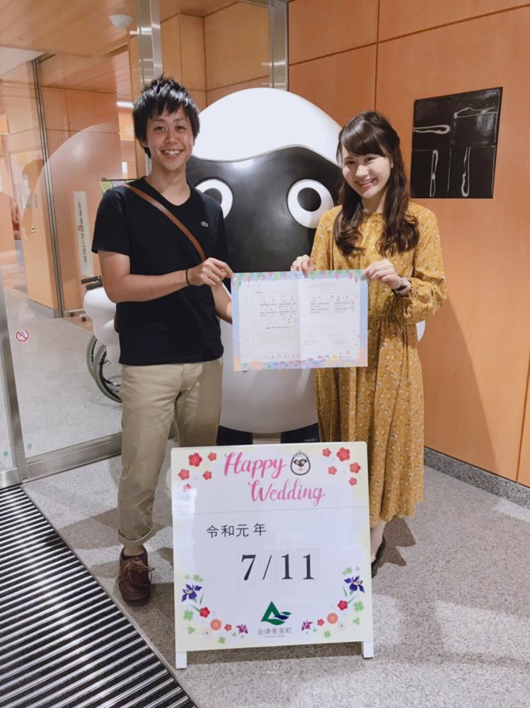 婚姻届記念撮影ボードの後ろに立った男女が婚姻届けを2人で持って記念撮影をしている写真