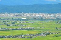 田園風景と山々、街並みが広がる写真