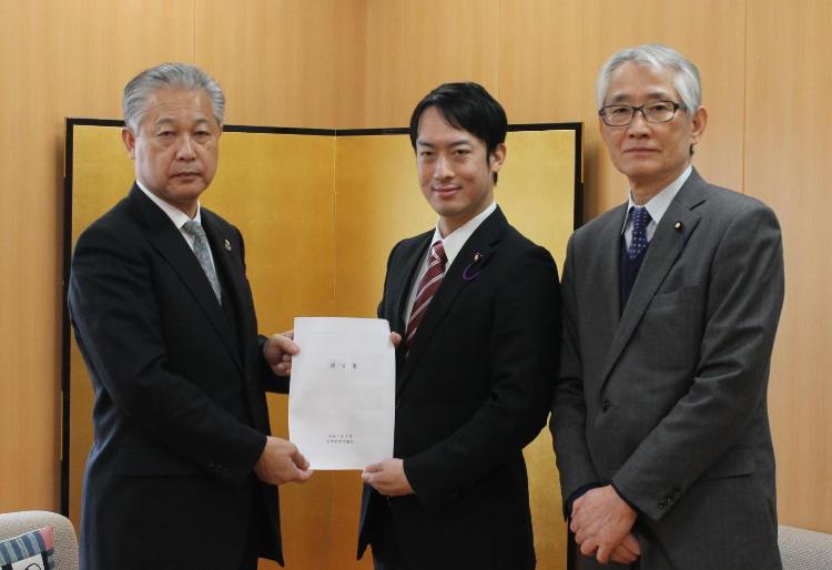 スーツを着た3人が横一列に並び、杉山町長と大竹議長が一緒に提言書を持っている写真