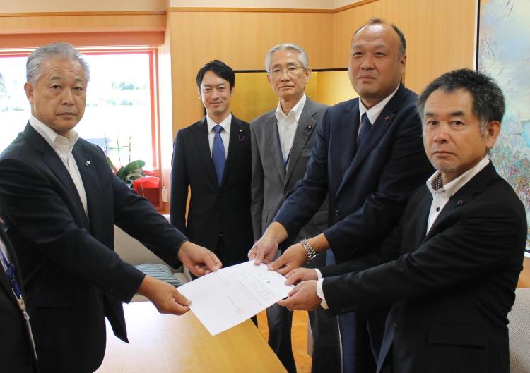 スーツを着た5人が横一列に並び、杉山町長と村松委員長、櫻井委員長が一緒に提言書を持っている写真