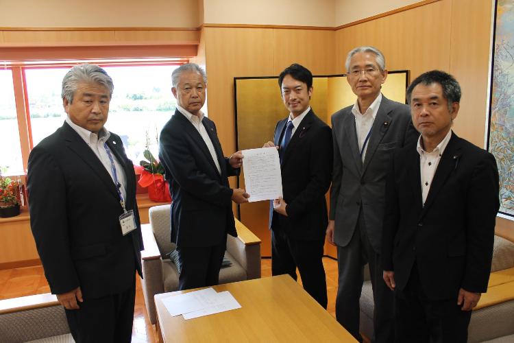 スーツを着た5人が横一列に並び、杉山町長と大竹議長が一緒に提言書を持っている写真