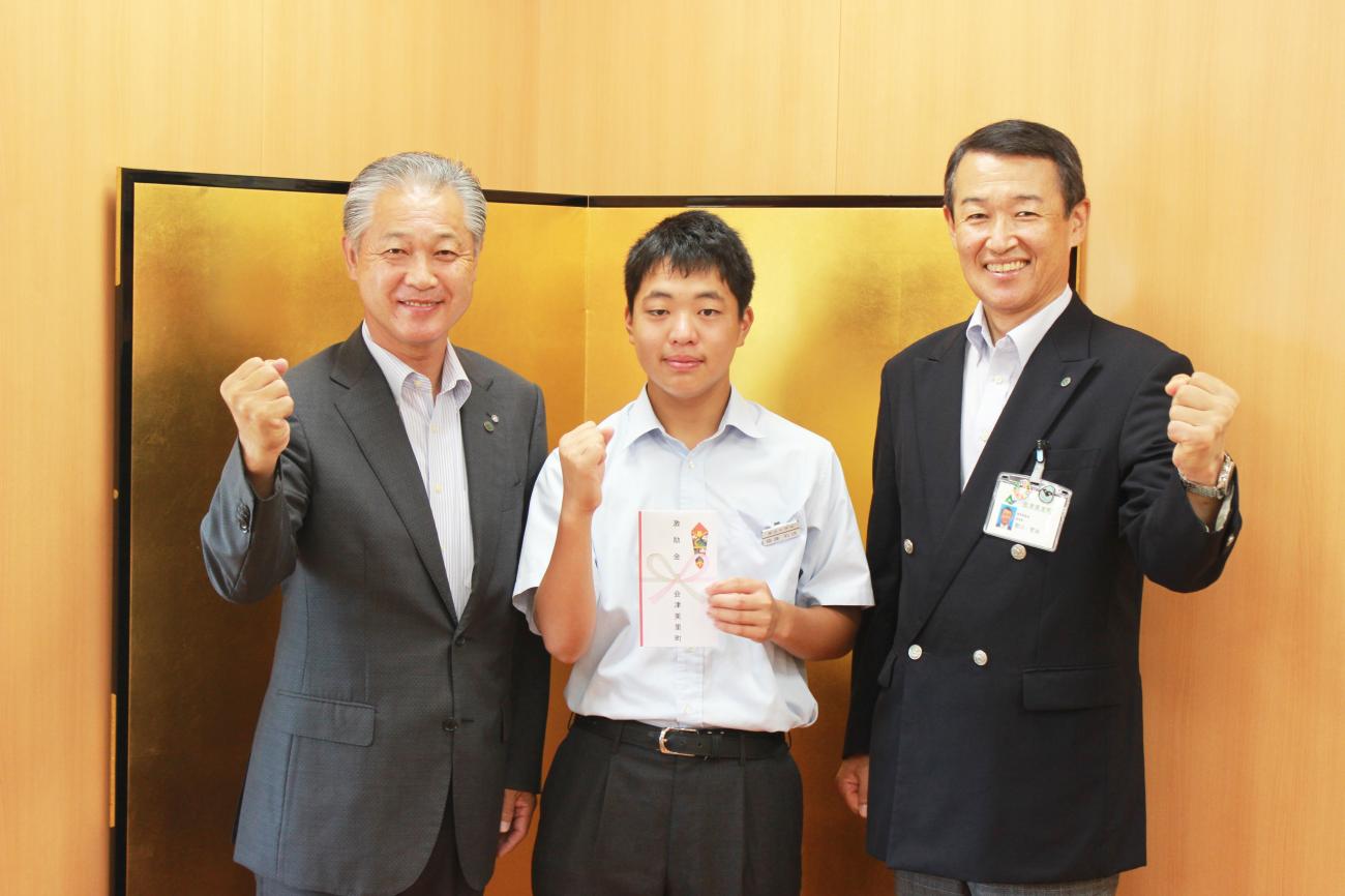 男性2名の中央に齋藤和瑛さんが立ち3名でガッツポーズをしている激励金交付時の写真