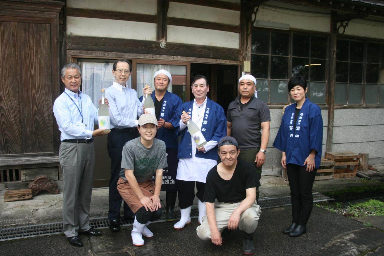 町長と福島県知事が両手でお酒を持ち、醸造所の皆さんと記念撮影をしている写真