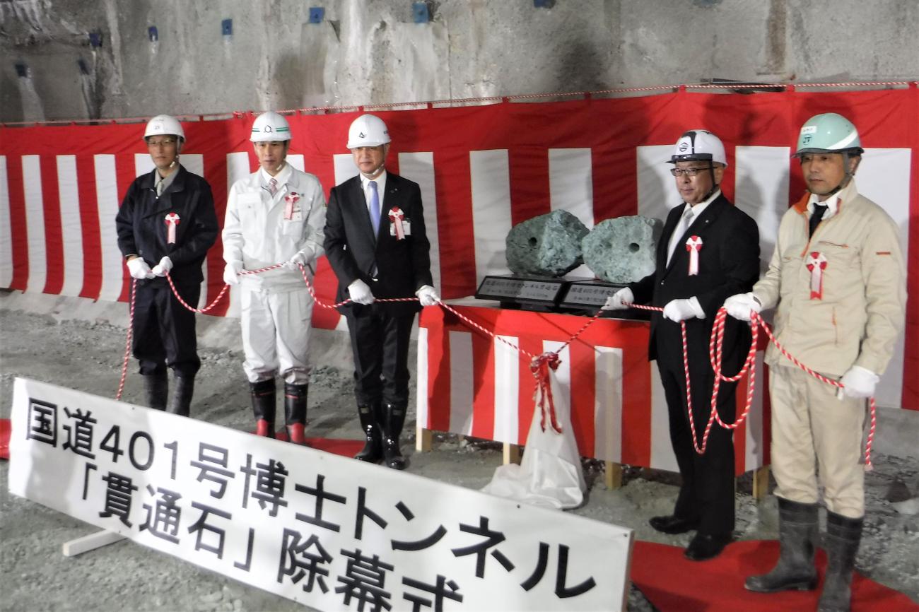 ヘルメット姿の男性5名が紅白の紐を持っている博士トンネル除幕式の写真