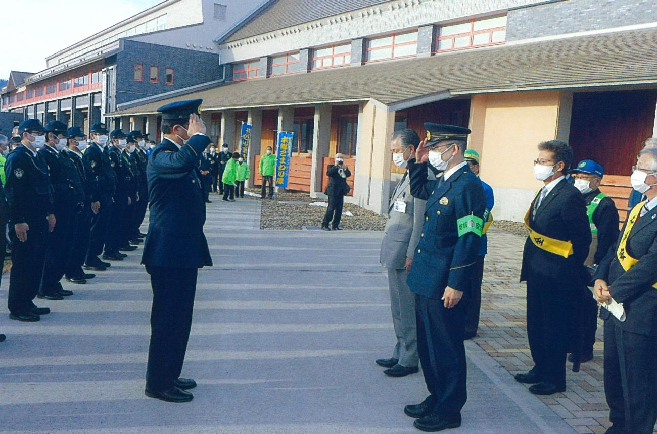 警察官の方々が1列に並び、代表者の男性が列の前に立って町長や関係者の方々に敬礼をしている写真