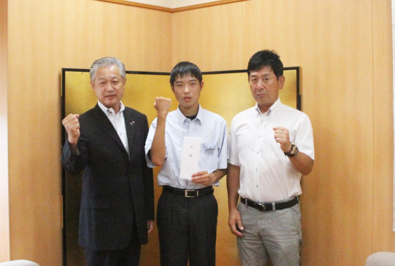 渡部勇輝さんの両隣に町長とYシャツを着た男性が立ち、3名でガッツポーズをしている写真