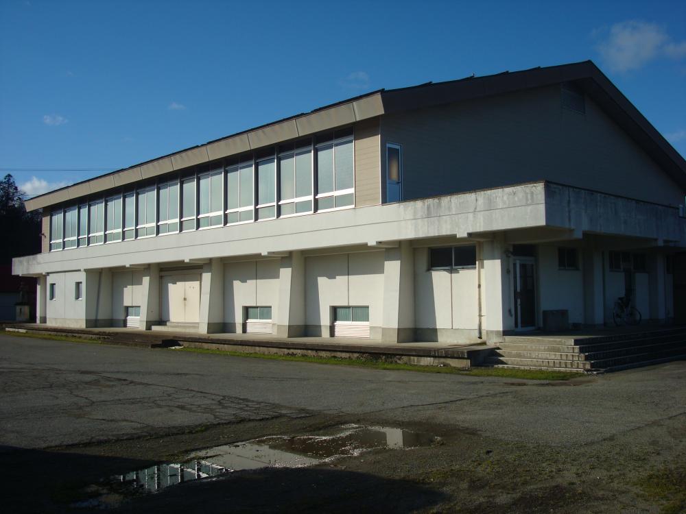 屋根が三角で2階部分に大きな窓が並んでいる旧旭小学校体育館の外観写真