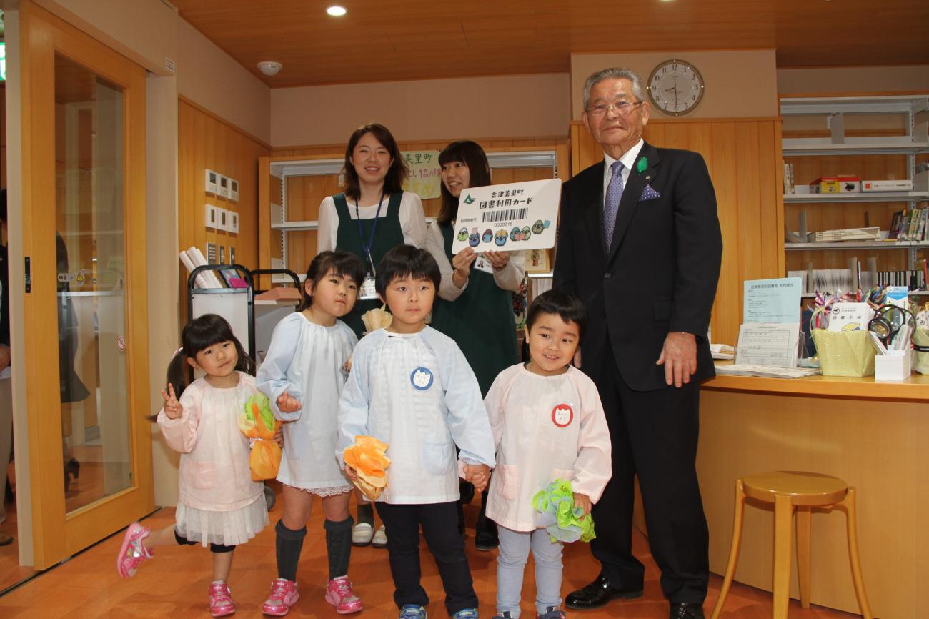 図書館のオープンで町長と職員の女性2名、男の子2名と女の子2名の園児が記念撮影をしている写真