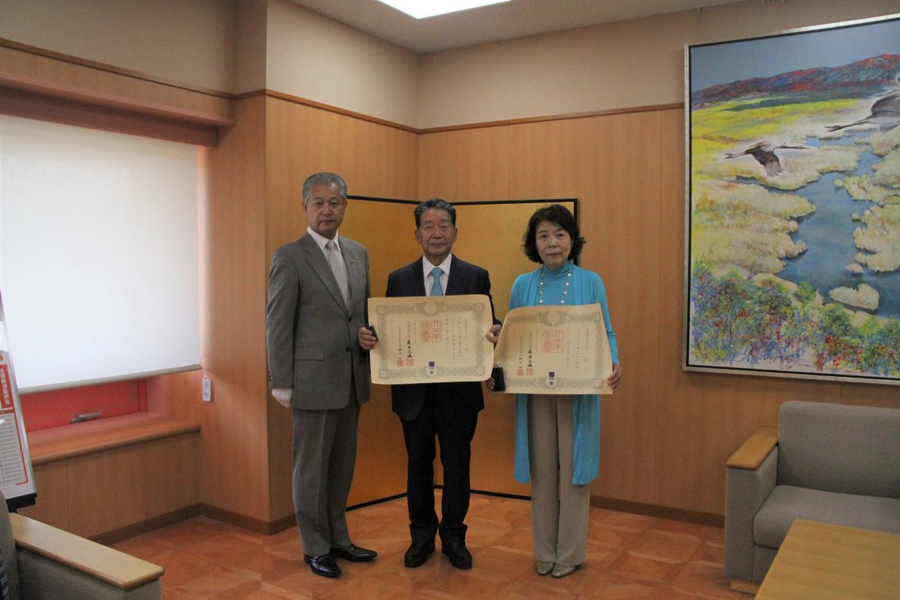 町長（左）と賞状を持った荒隆一さん（中央）と智子さん（右）が一緒に記念撮影をしている写真