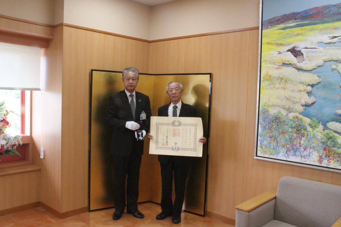 町長（左）は勲章を持ち、三星和夫さん（中央）は賞状を持って一緒に記念撮影をしている写真