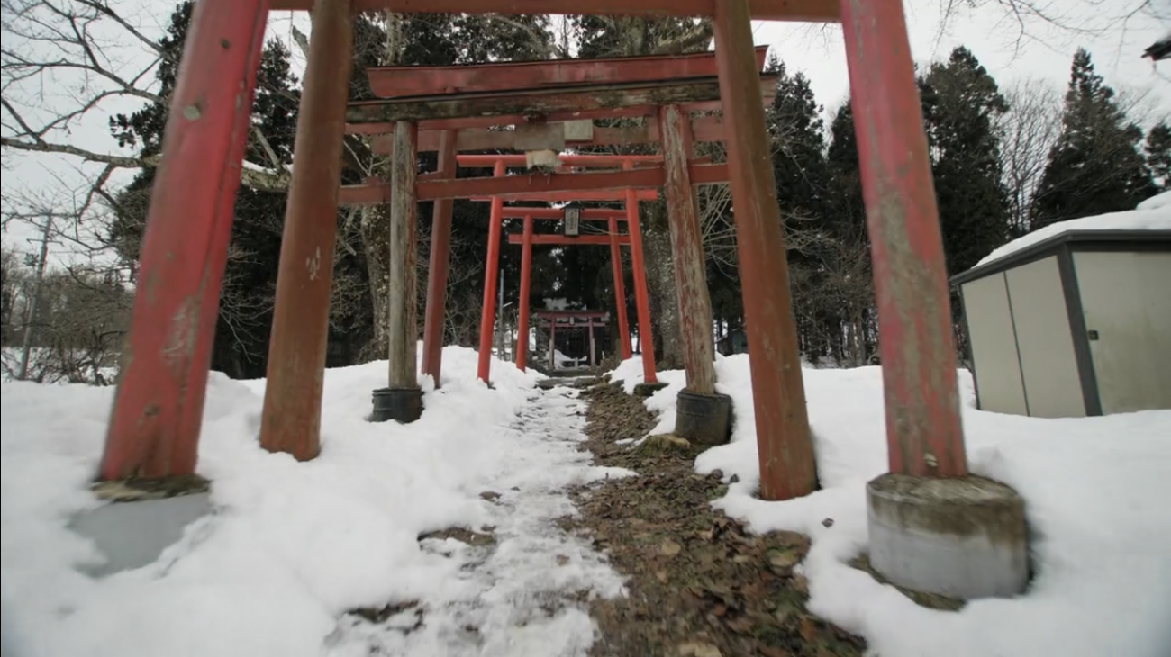 赤い鳥居が並んでおり、鳥居の周りは雪が積もっている所を正面足元から写した写真