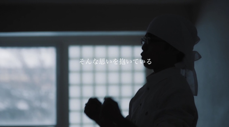 中央に「そんな思いを抱いている」とナレーションが書かれており、薄暗い部屋の中、タオルを巻いた人物が胸の前で手を握りしめている写真