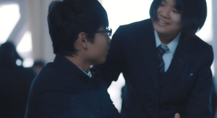 眼鏡をかけた男子生徒に笑顔で話しかけている女子生徒の写真