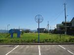 芝生の敷地に青いゾウの滑り台がある公園を道路から写した写真