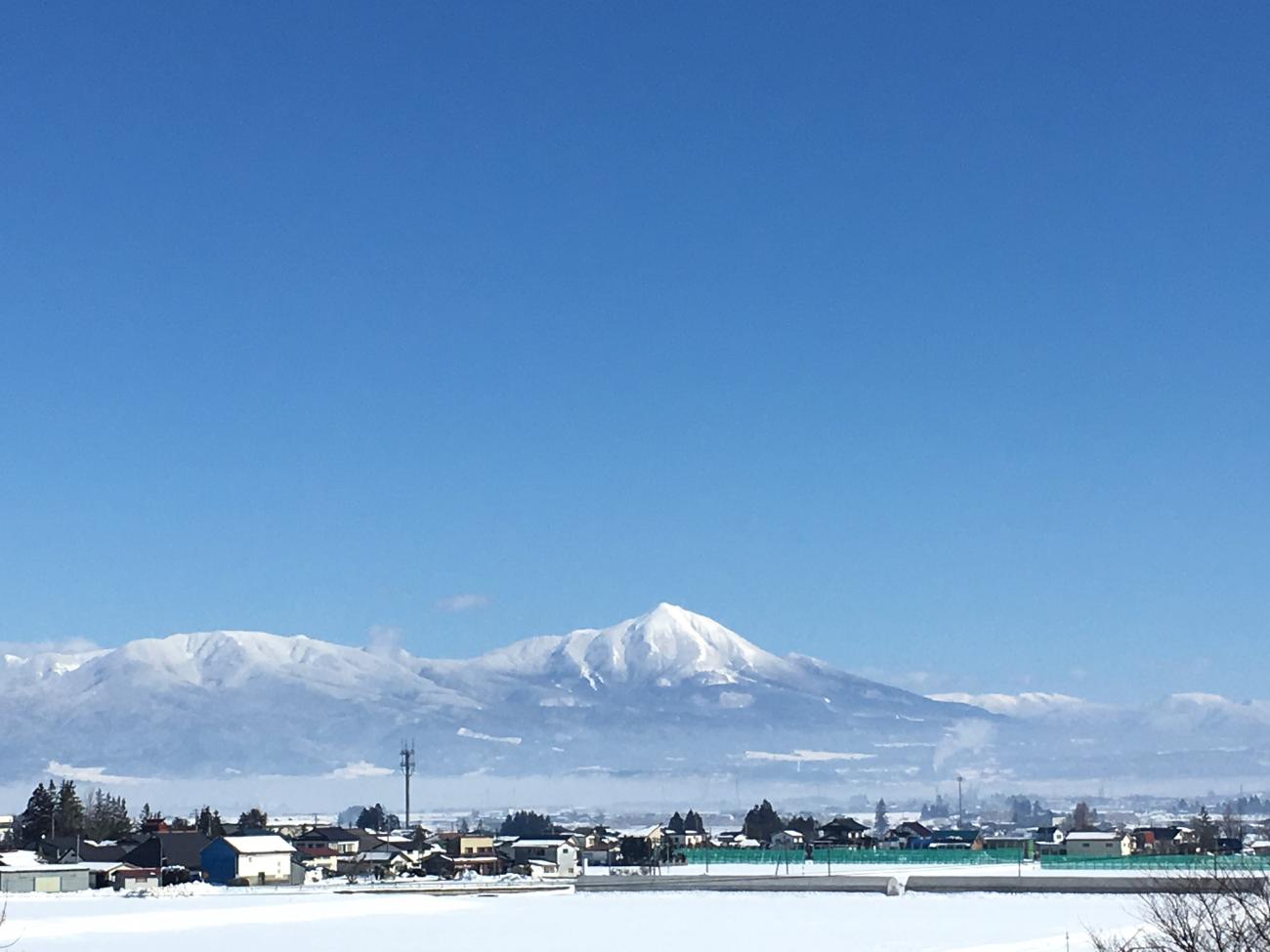 青空が広がる下に雪景色の街並みや山並みが写っている写真
