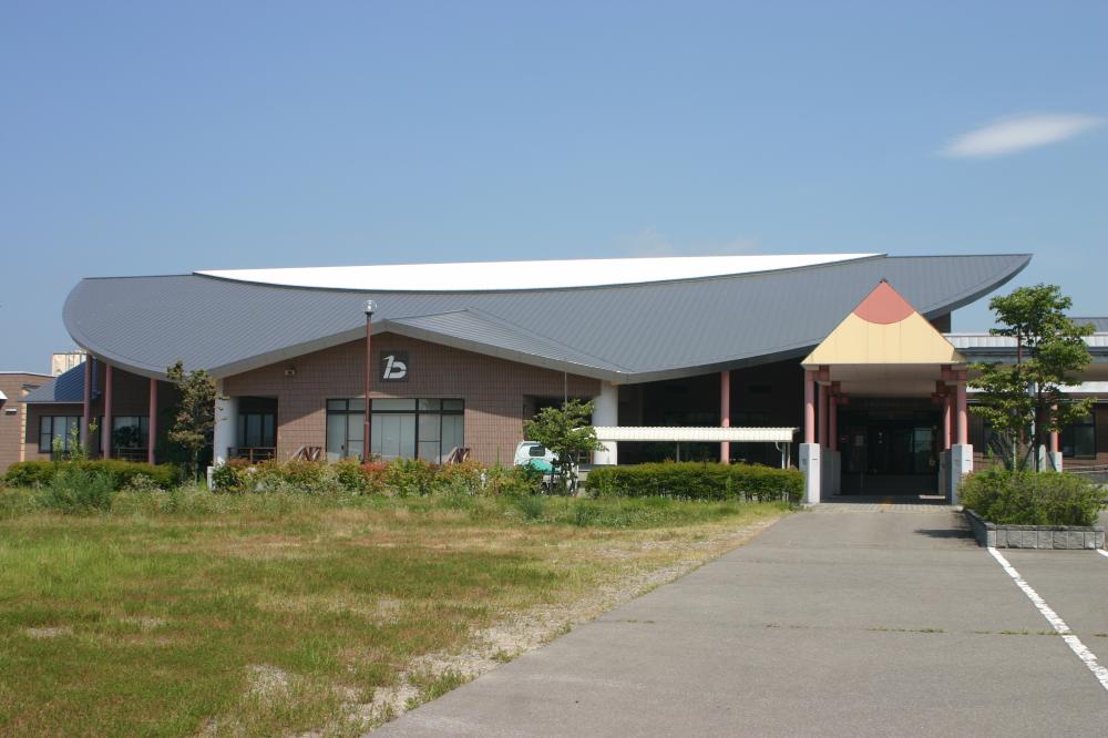 入口が鉛筆の形、平らな屋根をした新鶴高齢者福祉センターの外観写真