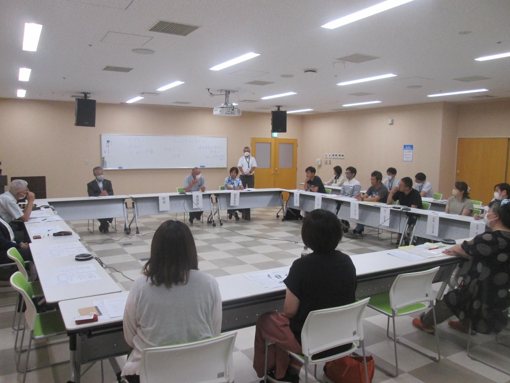 ロの字型に配置されたテーブルと椅子に座り話をしている協議会の様子の写真