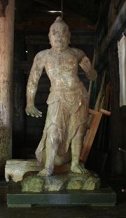 右手は下に、左手は胸元で拳を作り、睨んでいるような顔つきで立っている木造金剛力士像の写真