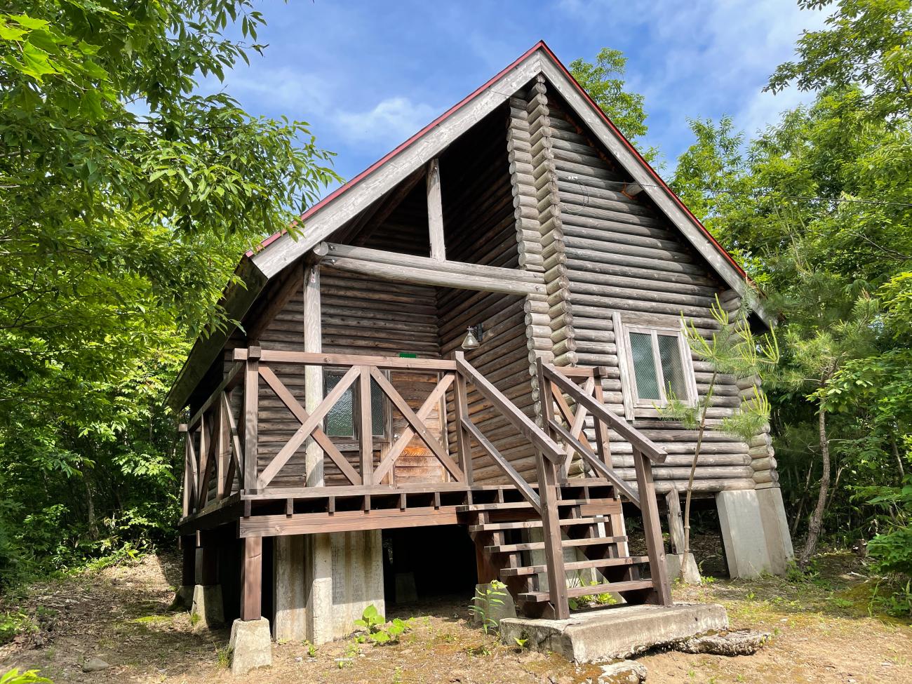 入口右側の部屋に窓があり、丸太を積み重ねて作られている赤い屋根のログハウス（小）南の写真