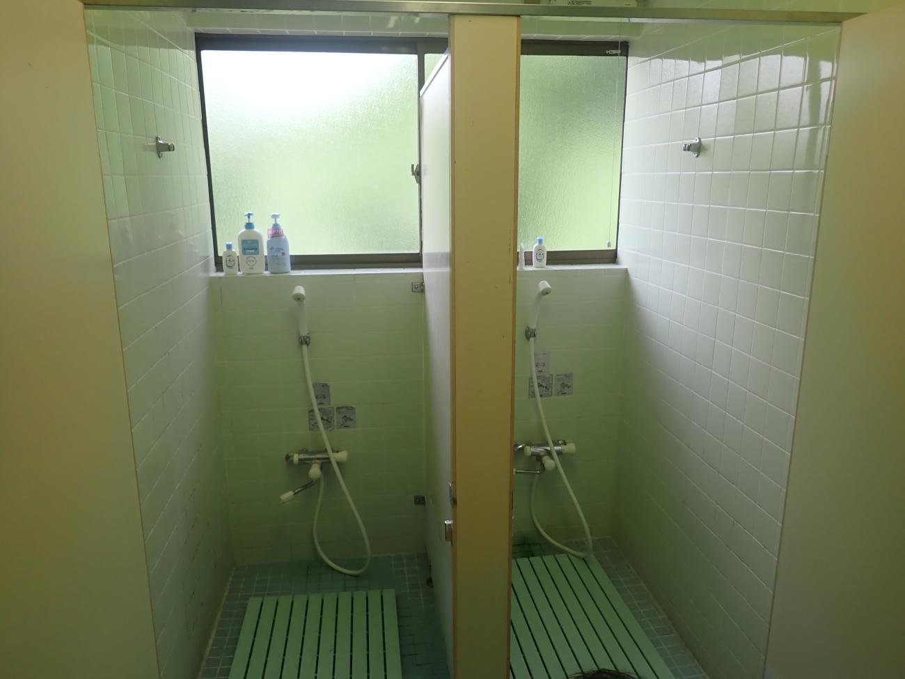 シャワー部屋が2つあり、窓枠にシャンプーやボディーソープが設置してある管理事務所内のコインシャワーの写真