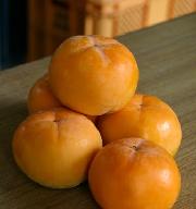 山積みにされている、オレンジ色の身不知柿の写真