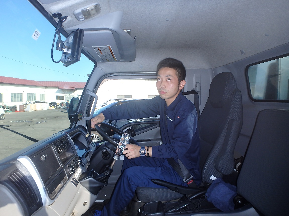 トラックを運転している男性の運転席を助手席側から写した写真
