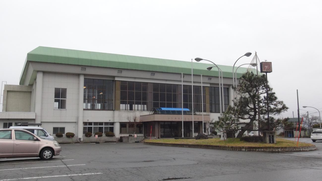 屋根が緑色をした高田体育館の駐車場から外観全体を写した写真