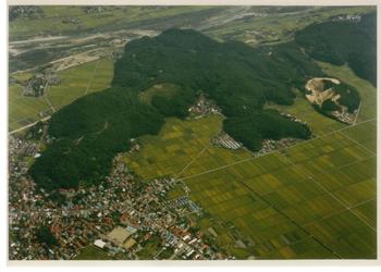 山脈の麓に家が建ち並び、周辺に田園が広がっている向羽黒山城跡の上空からの写真